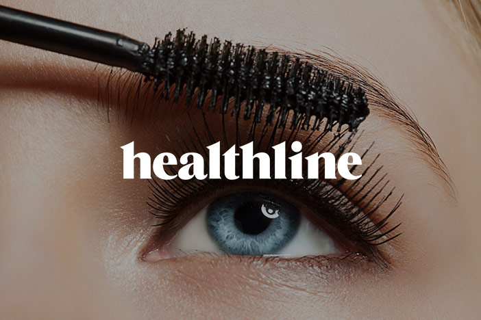 Mascara is applied to the lashes of a blue eye looking upwards. The 'Healthline' logo is superimposed on top.