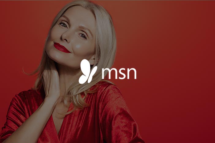 Dr Elizabeth Hawkes on festive season skin tips in MSN Smiling woman with healthy glowing skin against a red background, featured in MSN article about top skin tips for the festive season