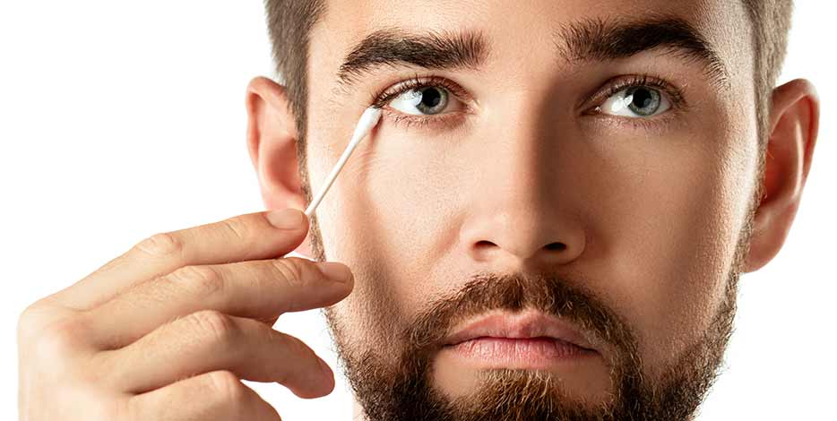 Man cleaning his eye with a cotton swab