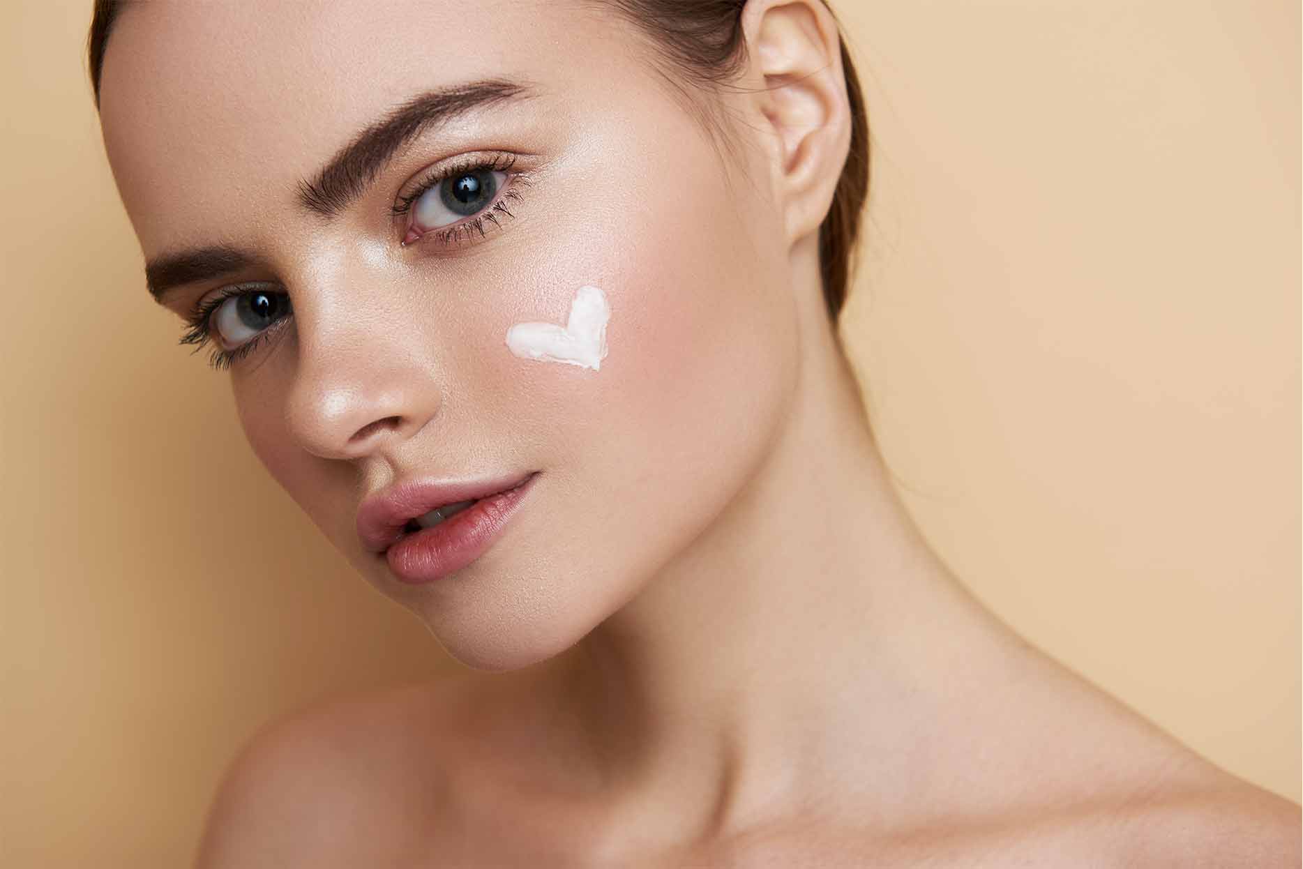 Close up of girl with white cream heart on the cheek