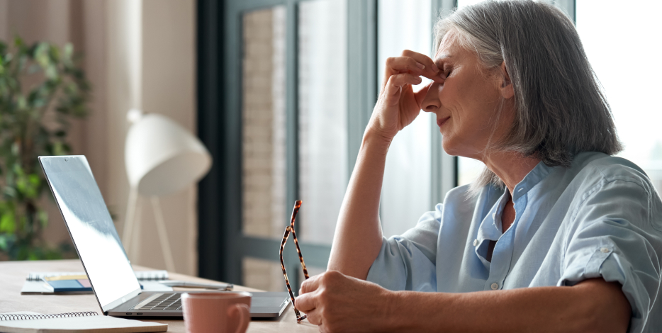 Senior business woman taking off glasses suffering from an eye problem