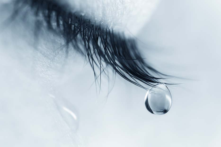title text Closed eyelid macro closeup with a teardrop on eyelashes running down