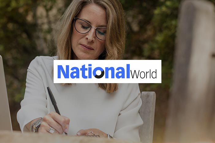 Middle aged woman writing at a desk with National World logo superimposed on top.