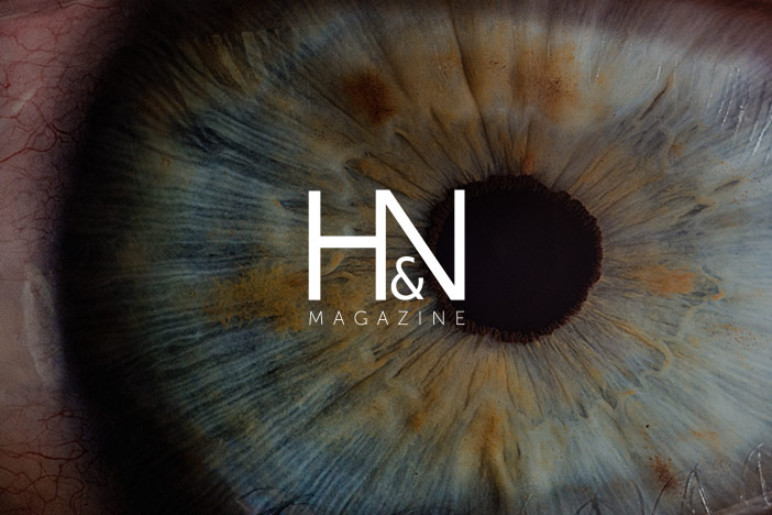 A macro shot of a blue eye looking into the camera lens. 'H&N Magazine' logo is superimposed in top.