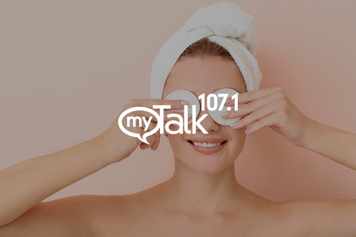 Younger woman with turban towel holds cotton pads to eyes. The 'myTalk 107.1' logo is superimposed on top. 
