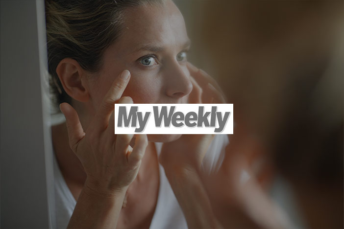 Middle aged woman examines her eyes in the mirror. The 'My Weekly' logo is superimposed on top.
