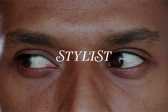 A middle aged man with brown eyes looks to the left while performing eye yoga. A 'Stylist' magazine logo is superimposed on top.