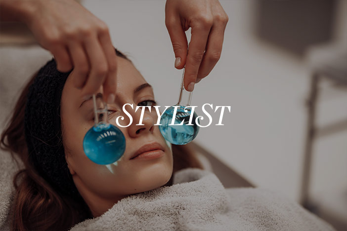 A beautiful woman has ice globes applied to her face in order to de-puff her eyes. 'Stylist' Magazine logo is superimposed on top.
