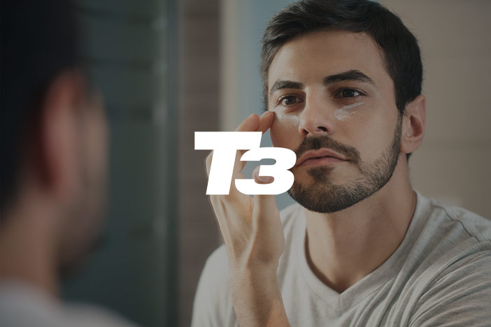 A younger man applies eye cream under the eye. The 'T3' logo is superimposed on top. 
