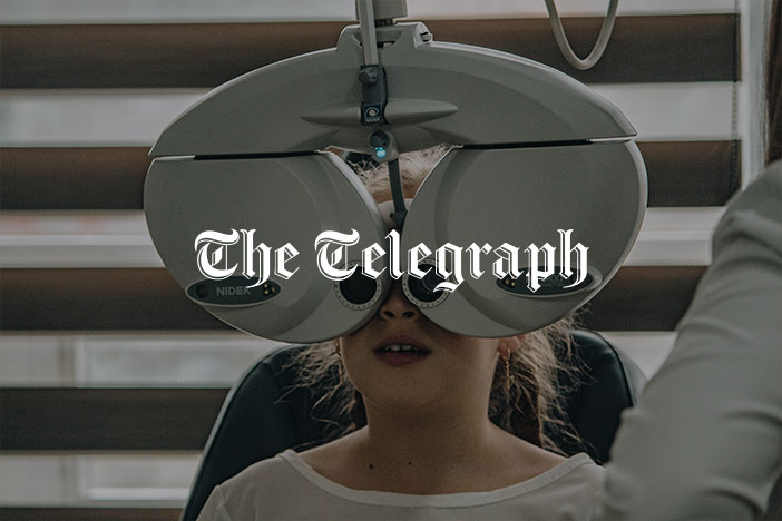 A female child is getting an eye test with The Telegraph logo superimposed on top