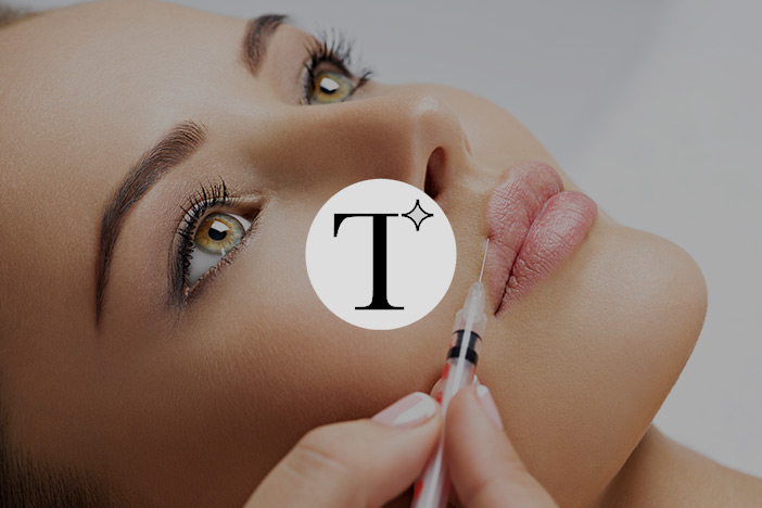 Younger woman receives a dermal filler injection to the lips. The 'Tweakment Guide' logo is superimposed on top.