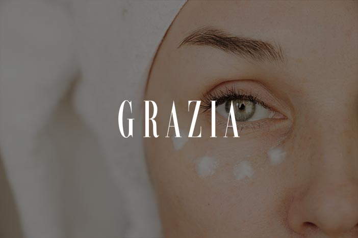 Close up of woman with towel on head applying eye cream dots under her eye for Grazia skincare feature