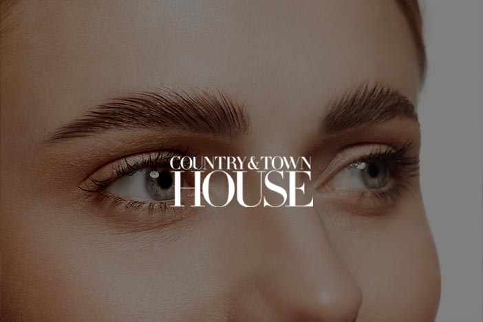 Close-up of a person’s well-defined eyebrows with the text 'Country & Town House' overlaying the image.