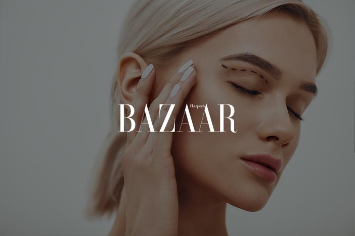 Dr Elizabeth Hawkes on blepharoplasty in Harper’s Bazaar Woman touching her temple with dotted pre-surgery markings above eyelid, featured in Harper’s Bazaar article about undergoing an eye lift