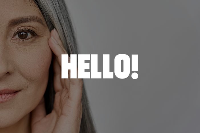 Mature woman with grey hair touching her cheek, Hello feature on filler