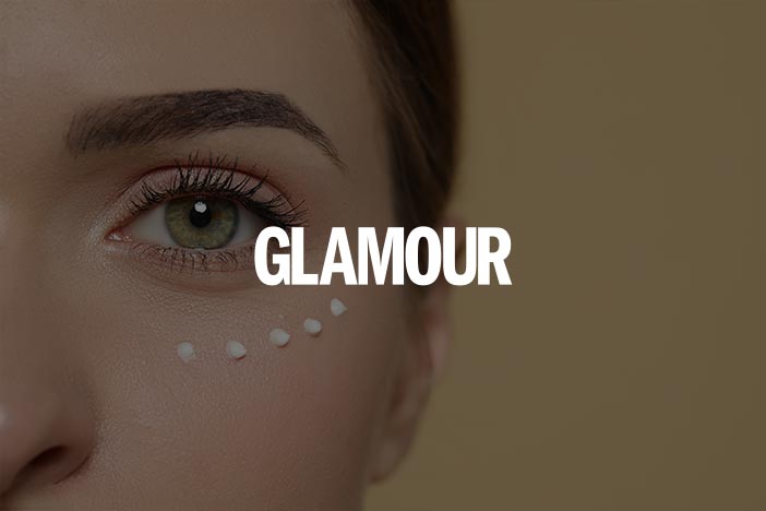 Close-up of a woman's eye with small dots of eye cream applied under it, featuring the text "Glamour" overlaid