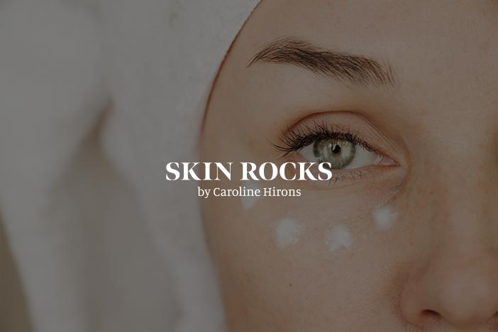 Close-up of a person's face with skincare dots under the eye, featuring the 'Skin Rocks by Caroline Hirons' logo.