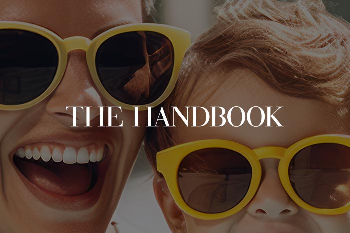 Smiling woman and child wearing bright yellow sunglasses, featured in The Handbook article about treating sunburn