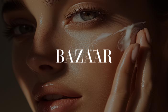 Close-up of a woman applying skincare cream to her face featured in Harper’s Bazaar retinol advice article