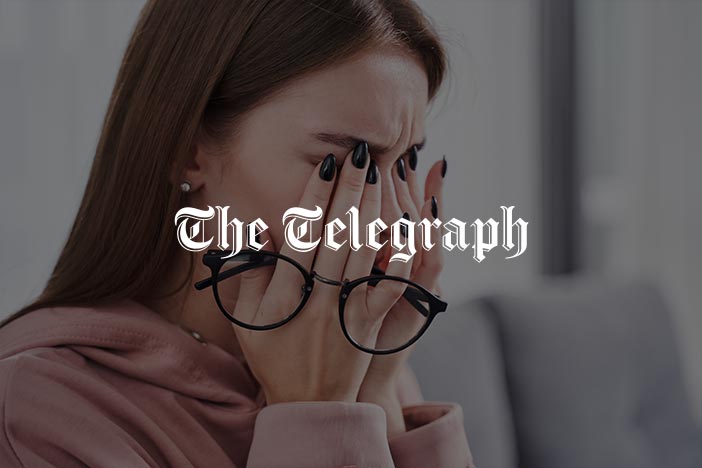 The Telegraph article on causes and remedies for dry eyes Woman rubbing her eyes while holding glasses, showing signs of eye strain