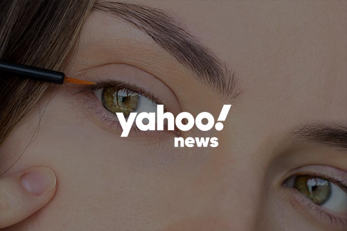 Close-up of a person applying eyelash growth serum on eyelids with the Yahoo! News logo overlaid.