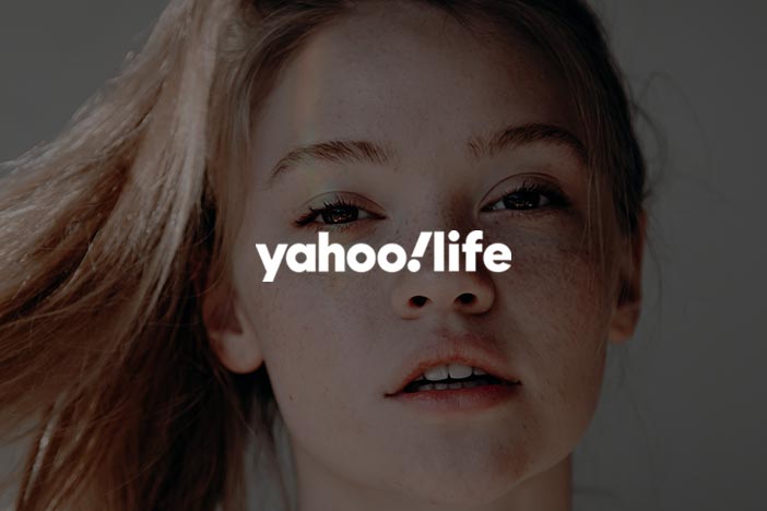 Close-up of a young woman with freckles with Yahoo Life logo, illustrating discussions on cosmetic surgery's impact on youth.