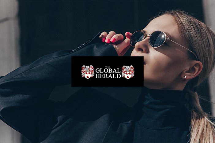 Woman in sunglasses looks upward with The Global Herald logo superimposed